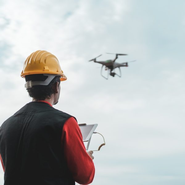 male engineer monitoring construction site with drone technology and industrial concept